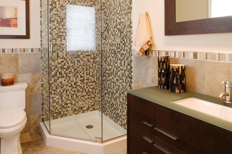 В этой маленькой ванной 4 кв м дизайн строится вокруг акцентной стены в душевой, которую выложили мозаикой.